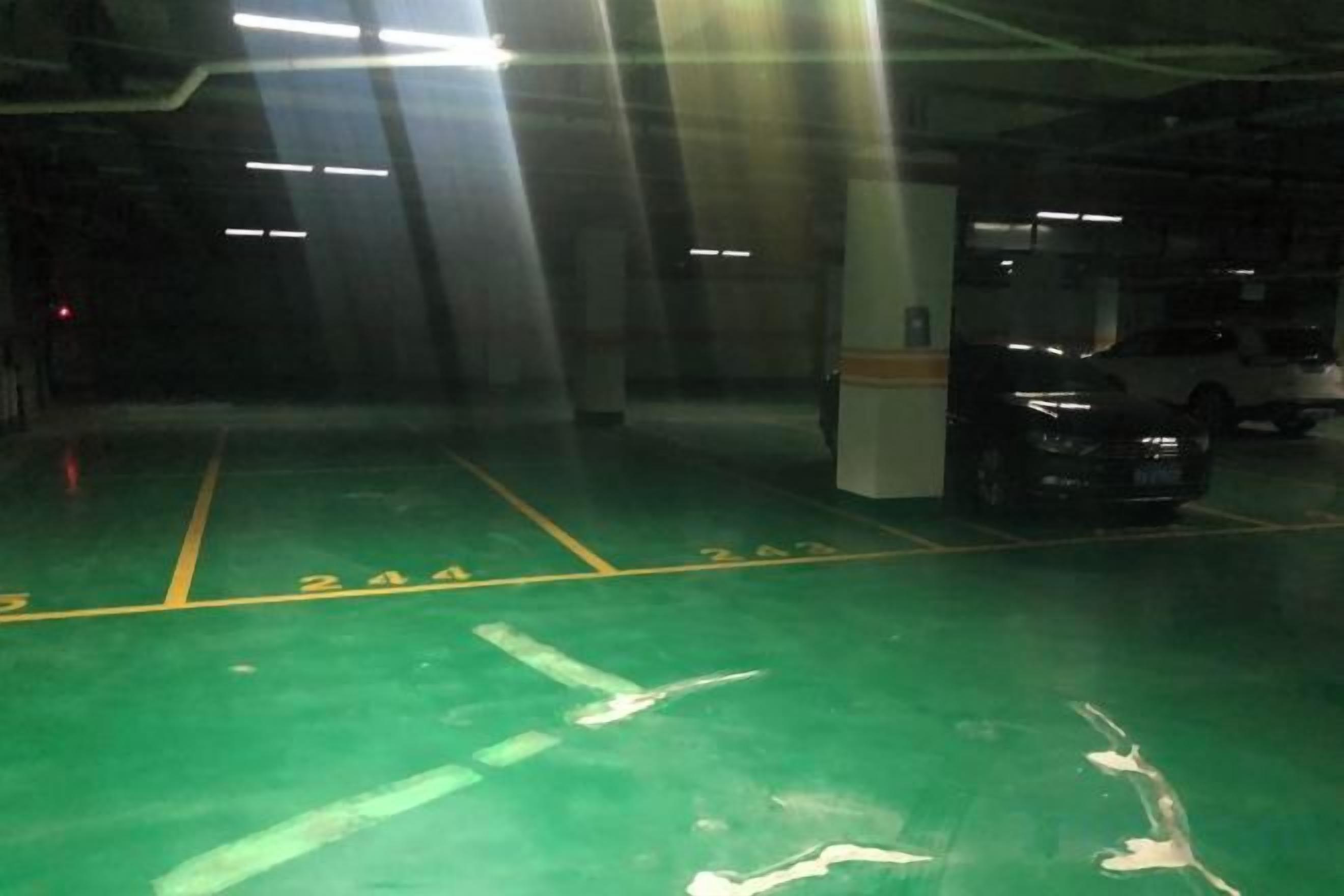 A parking garage with green flooring and white lines marking parking spaces.
