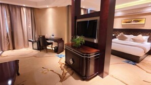 A hotel room with a bed, a desk, a chair, and a television.