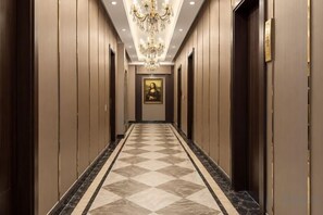 A hotel hallway with a checkered floor, a chandelier, and doors on either side. - Meijia Jiahua Hotel (Shangzhi)