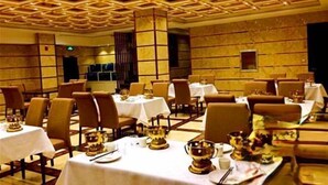 A dining area with tables set for service, featuring a geometric ceiling design and marble walls.