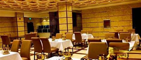 A dining area with tables set for service, featuring a geometric ceiling design and marble walls.