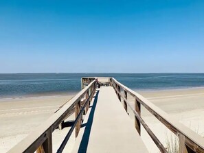 A wooden boardwalk leading to a beach with a clear blue sky. - Sea's the Day (Tybee Island)