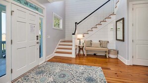 A staircase with wooden steps and white railings leading to a landing with a bench and a lamp. - Stunning Marsh Views, 5 Bedroom 6.5 Bath with pool (Saint Simons Island)