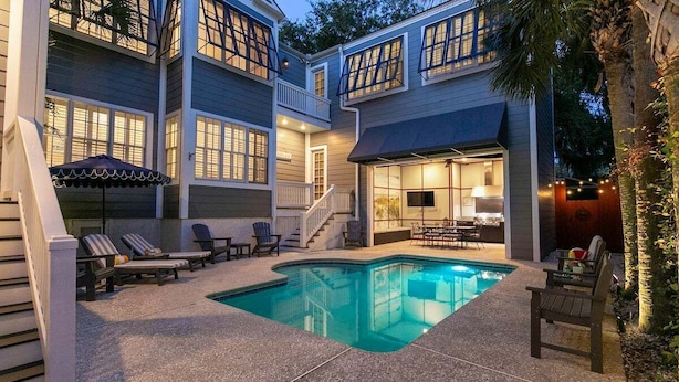 A two-story house with a swimming pool, outdoor seating, and a covered patio area. - Stunning Marsh Views, 5 Bedroom 6.5 Bath with pool (Saint Simons Island)