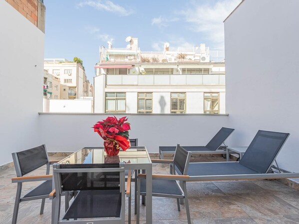 Un balcón con una mesa, sillas y una planta en maceta.