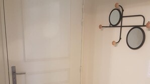 Eine weiße Tür mit silbernem Griff und ein an der Wand befestigter Spiegel mit schwarzem Rahmen und Holzapplikationen.
