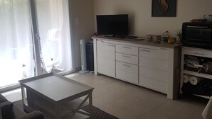 Ein modernes Wohnzimmer mit Flachbildfernseher, Esstisch und einer Couch.