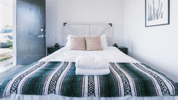 A bedroom with a bed, a headboard, a nightstand, a door, and a framed picture on the wall. - Fillmore Lodge:Comfortable Queen Room - Best Price (Fillmore)