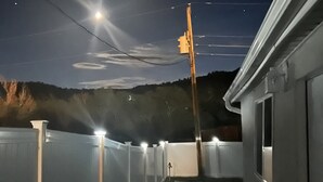 Ein von Zäunen umgebener Außenbereich mit freier Sicht auf den Himmel und eine ferne Hügellandschaft.