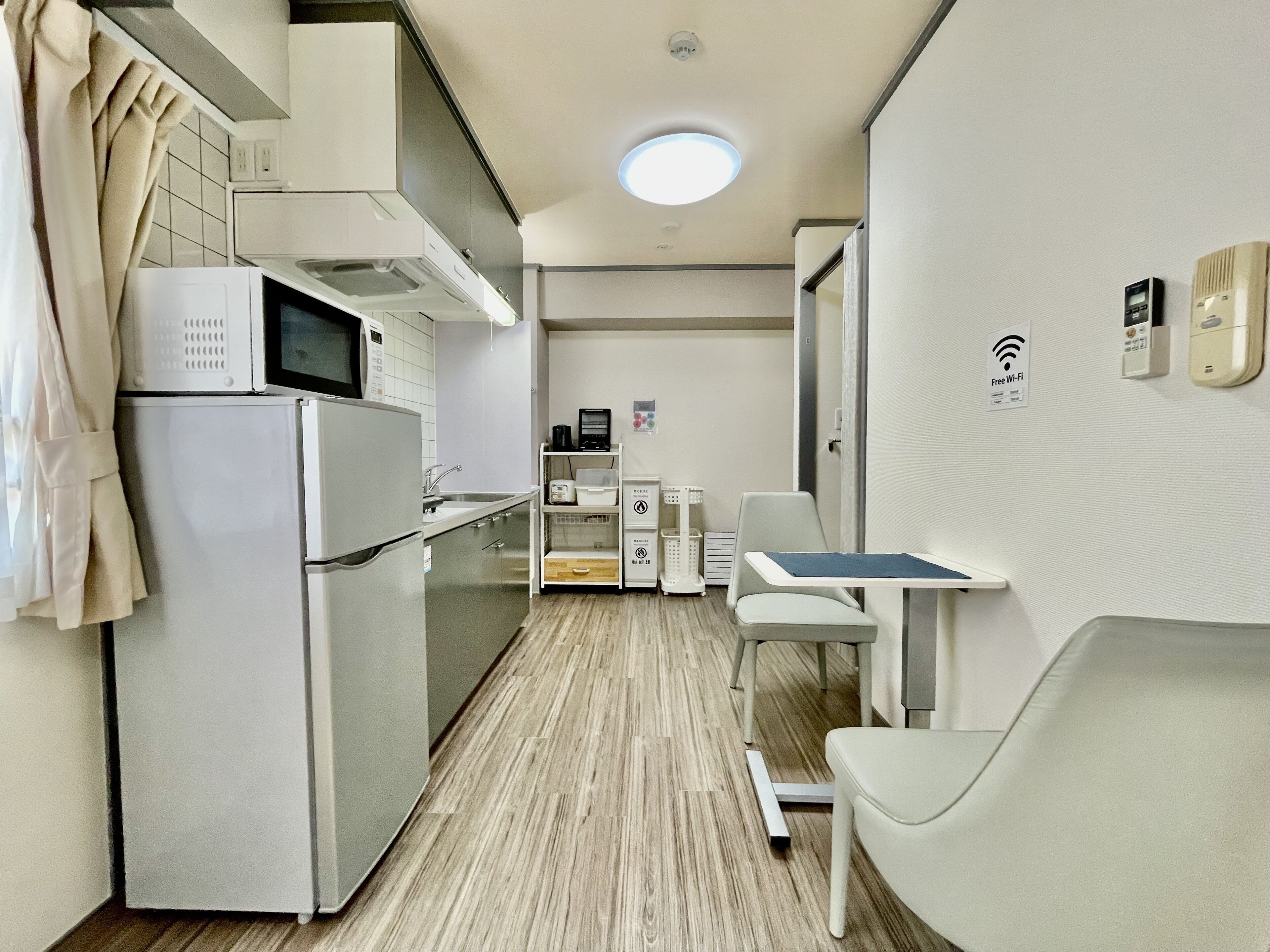 A compact kitchen with a microwave, refrigerator, and a small dining area with a table and chairs.