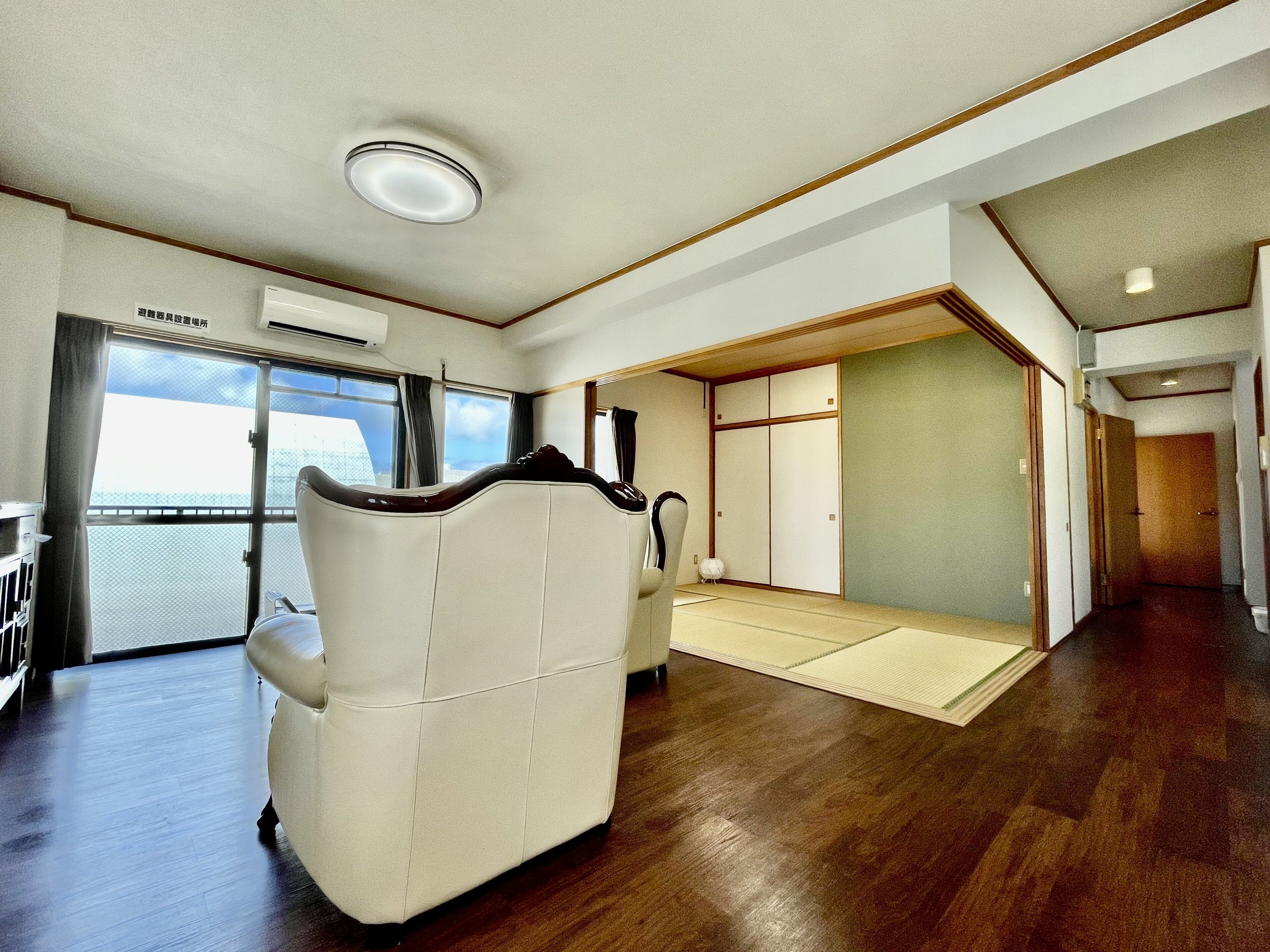 Ein geräumiger Raum mit großem Fenster, Massagesessel und einer Tatami-Matten-Ecke.