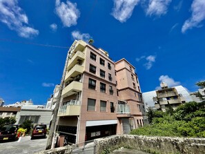 Un edificio a più piani con tetto piatto, balconi e ingresso al piano terra.