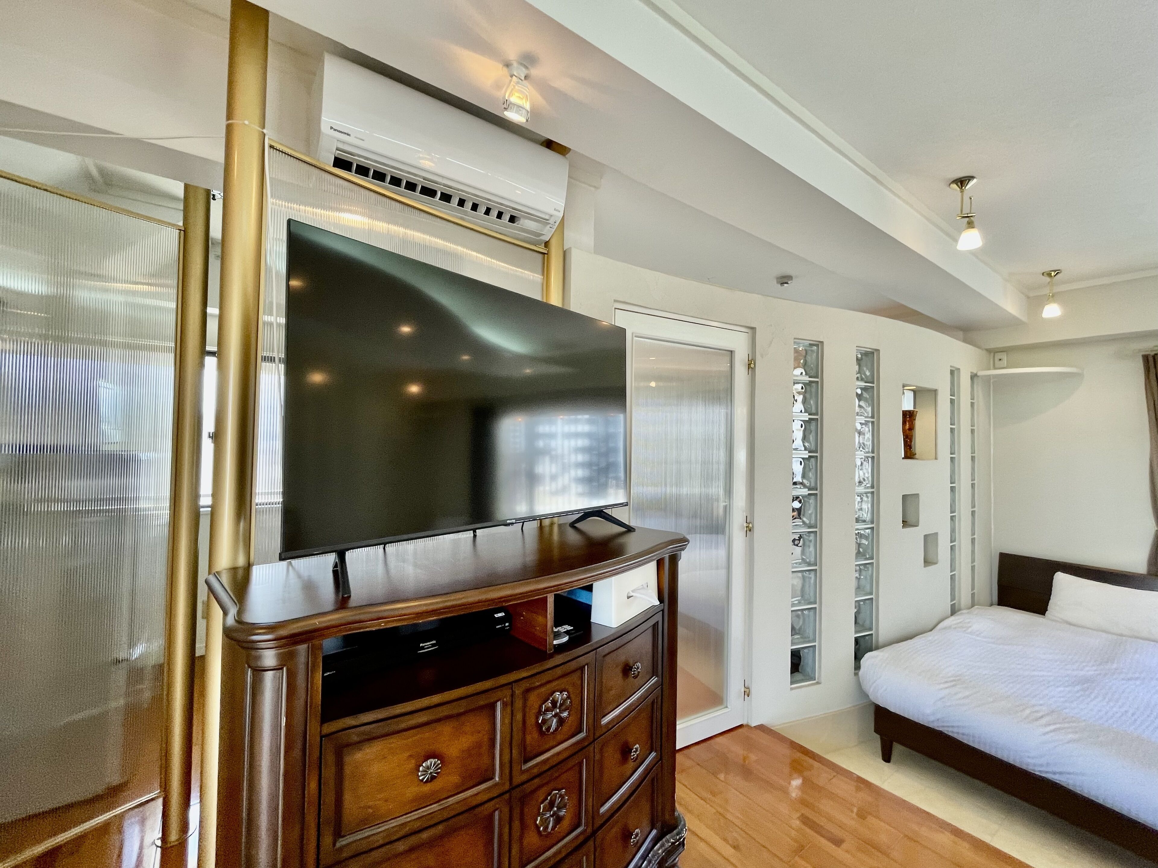 Camera d'albergo con una grande televisione a schermo piatto, una cassettiera in legno e un letto.