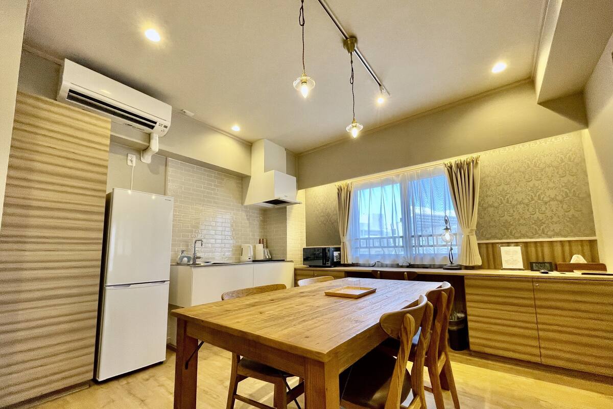 Eine kompakte Küche mit Essbereich, mit einem Holztisch, Stühlen und einem eingebauten Backofen.