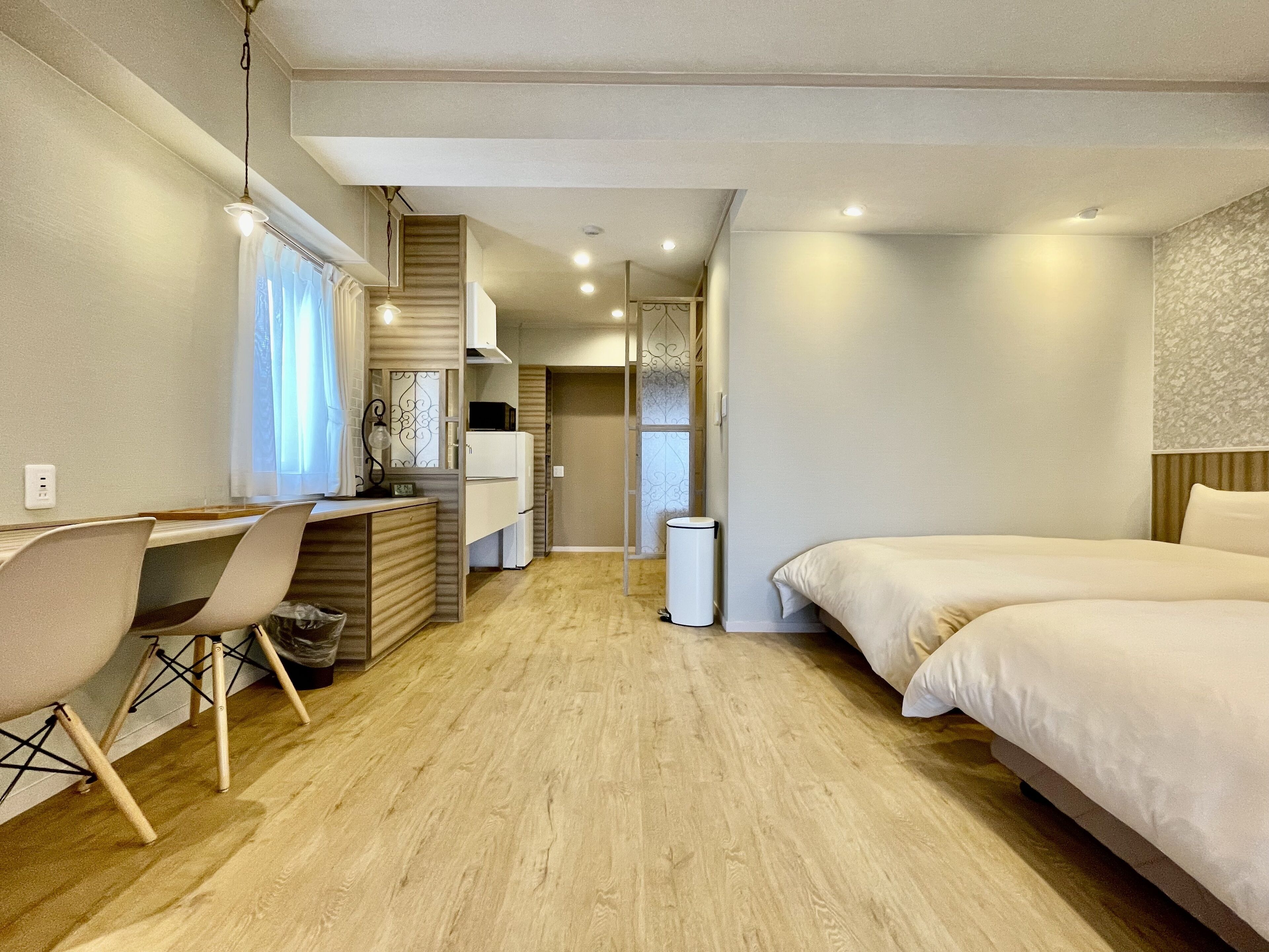 A compact hotel room with a bed, a desk with a chair, a small kitchenette, and a bathroom.