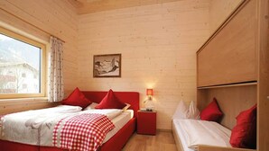 A room with a large bed, a smaller bed, a nightstand, a lamp, and a painting on the wall. - Lodge with sauna in the centre of Kaprun (Kaprun)