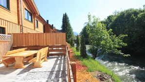 A wooden building with a river view, outdoor seating, and a wooden deck. - Lodge with sauna in the centre of Kaprun (Kaprun)