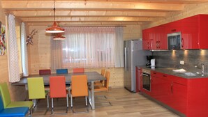 A compact kitchen with red cabinets, a stainless steel refrigerator, and a sink. - Lodge with sauna in the centre of Kaprun (Kaprun)