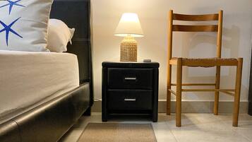 Un dormitorio con una cama, una mesita de noche con lámpara, una silla y una alfombra.
