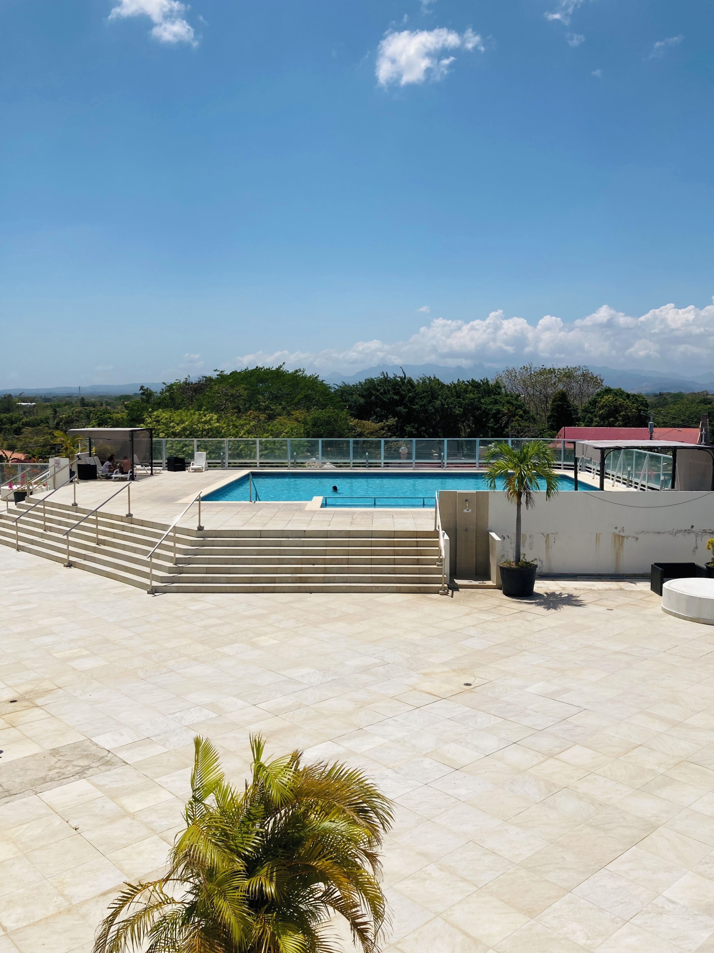 Una piscina en la azotea con vistas despejadas del paisaje circundante, incluyendo montañas lejanas y vegetación.