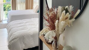 A bedroom with two beds, a large mirror, and a decorative shelf with plants. - Apartment in Coronado: Just steps from the beach, restaurants, cafes, and bars (Las Lajas)
