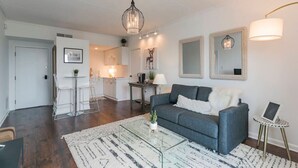 Een moderne woonkamer met een grijze bank, een glazen salontafel en een kroonluchter.