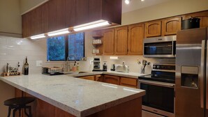 Una cocina moderna con gabinetes de madera, electrodomésticos de acero inoxidable y encimera de granito.