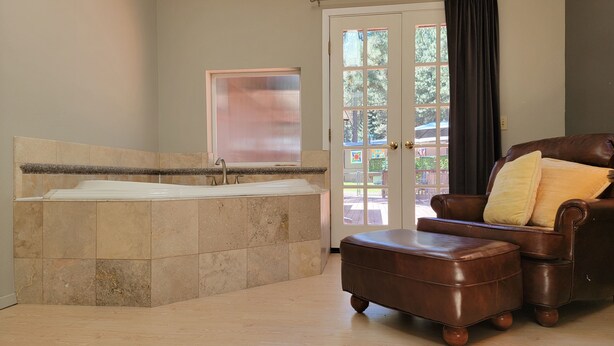Un baño con bañera, lavamanos y una puerta que da al exterior.