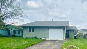 A single-story house with a garage, a small front yard, and a cloudy sky. - Hathaway- single level - KING BED (Corvallis)