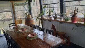Een houten eettafel met stoelen, omringd door potplanten en een hanglamp.