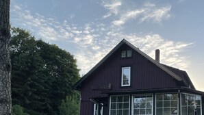 Een gebouw met twee verdiepingen, een donkere gevel, grote ramen en een stenen fundering.