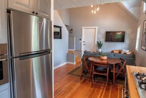 Enjoy cooking in the fully equipped kitchen with a gas stove and refrigerator, and relax in the adjacent living area with a flat-screen TV and comfortable seating.
