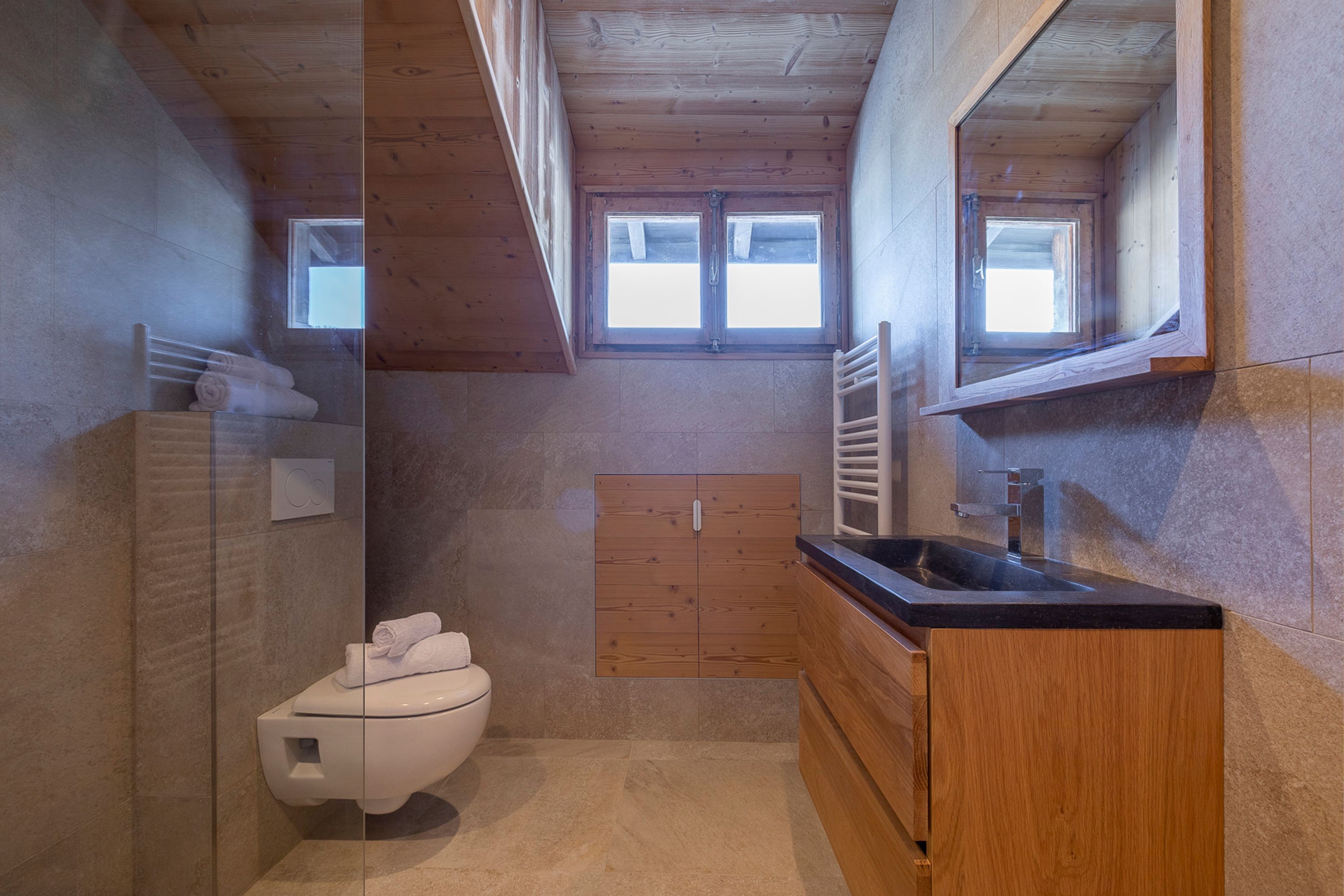 Un baño moderno con techo de madera, lavamanos integrado y retrete.