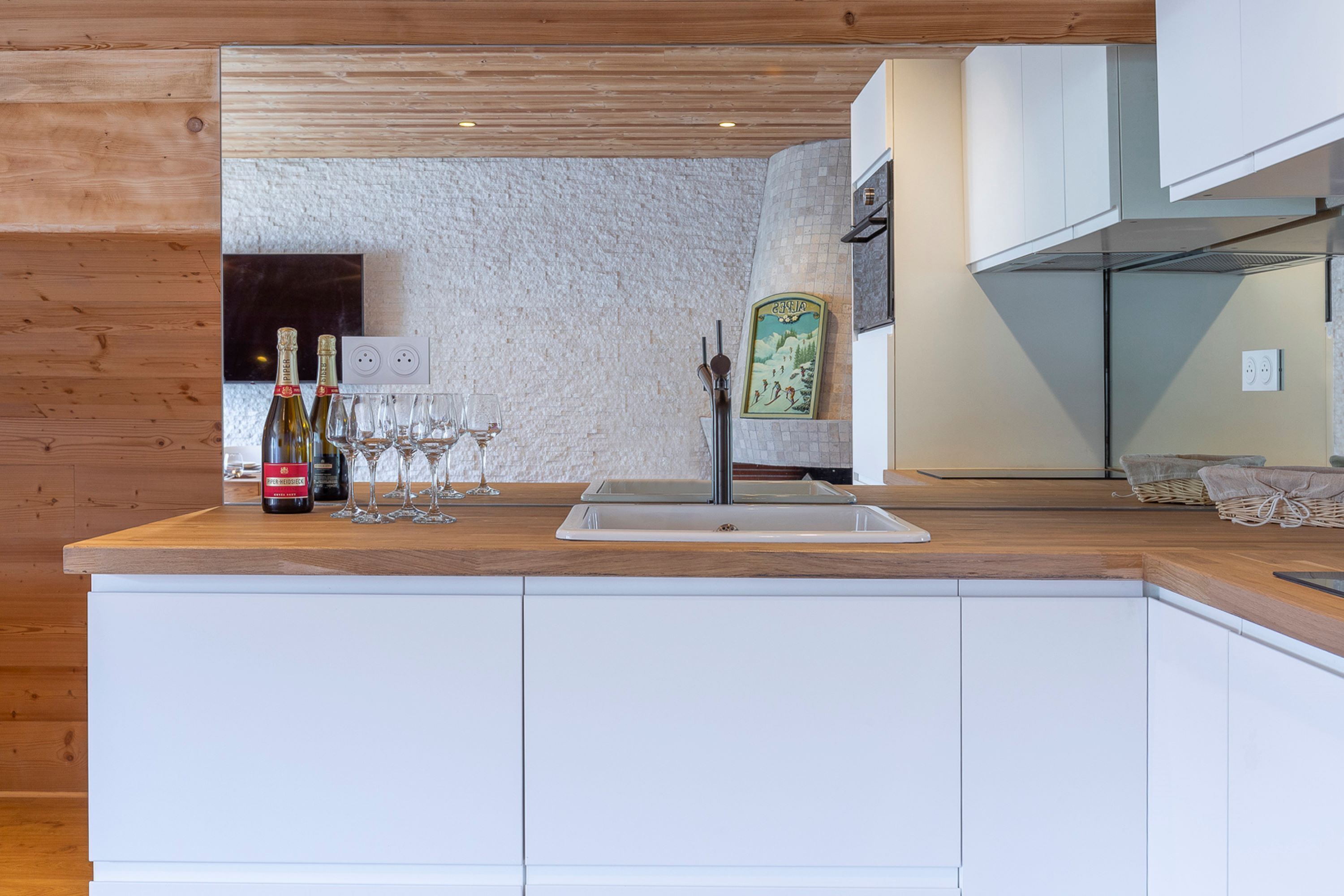 Une cuisine moderne avec un plan de travail en bois, des armoires blanches et un évier encastré.