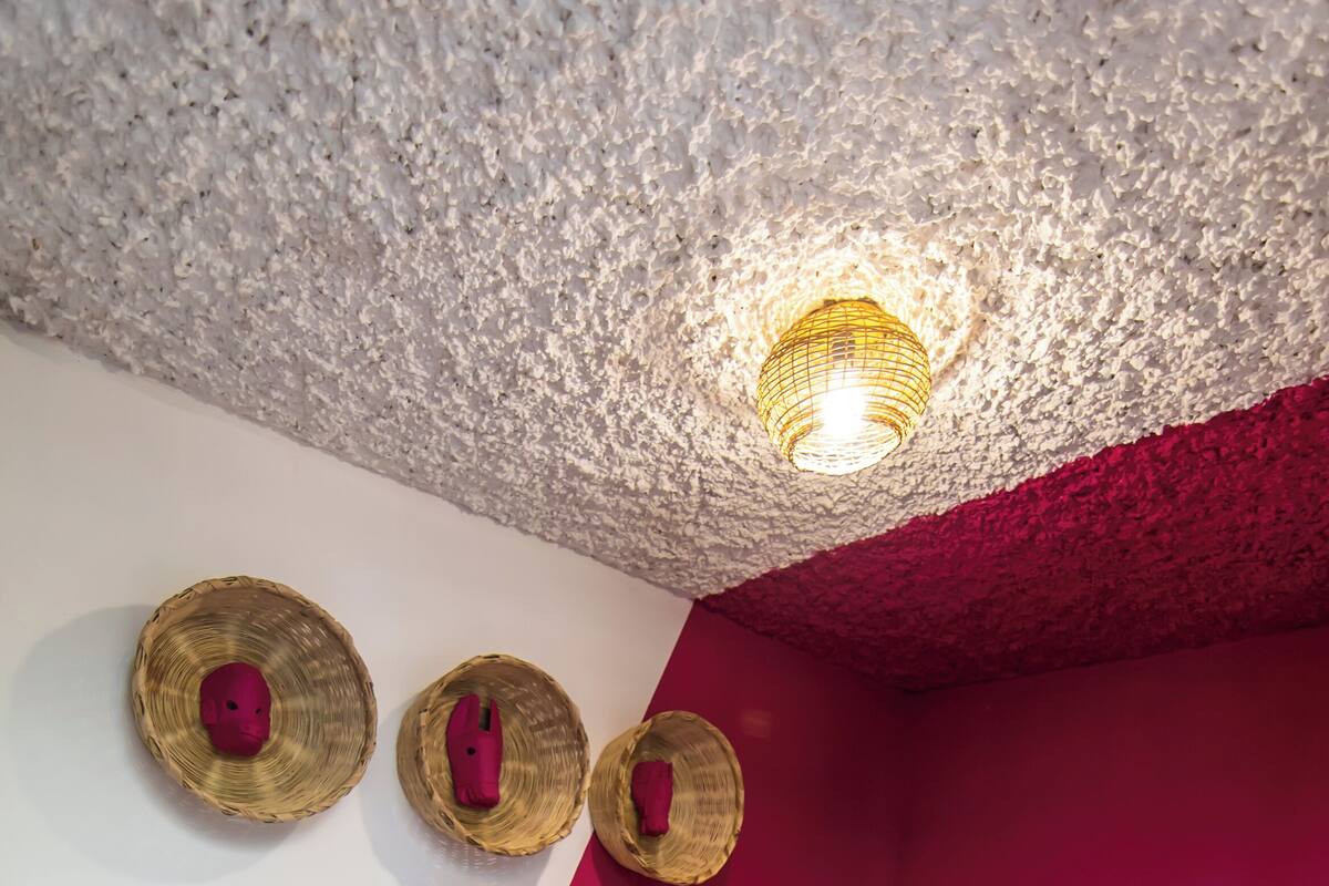 A bedroom with a bed, a headboard, a wall-mounted light fixture, and three wall-mounted hats.