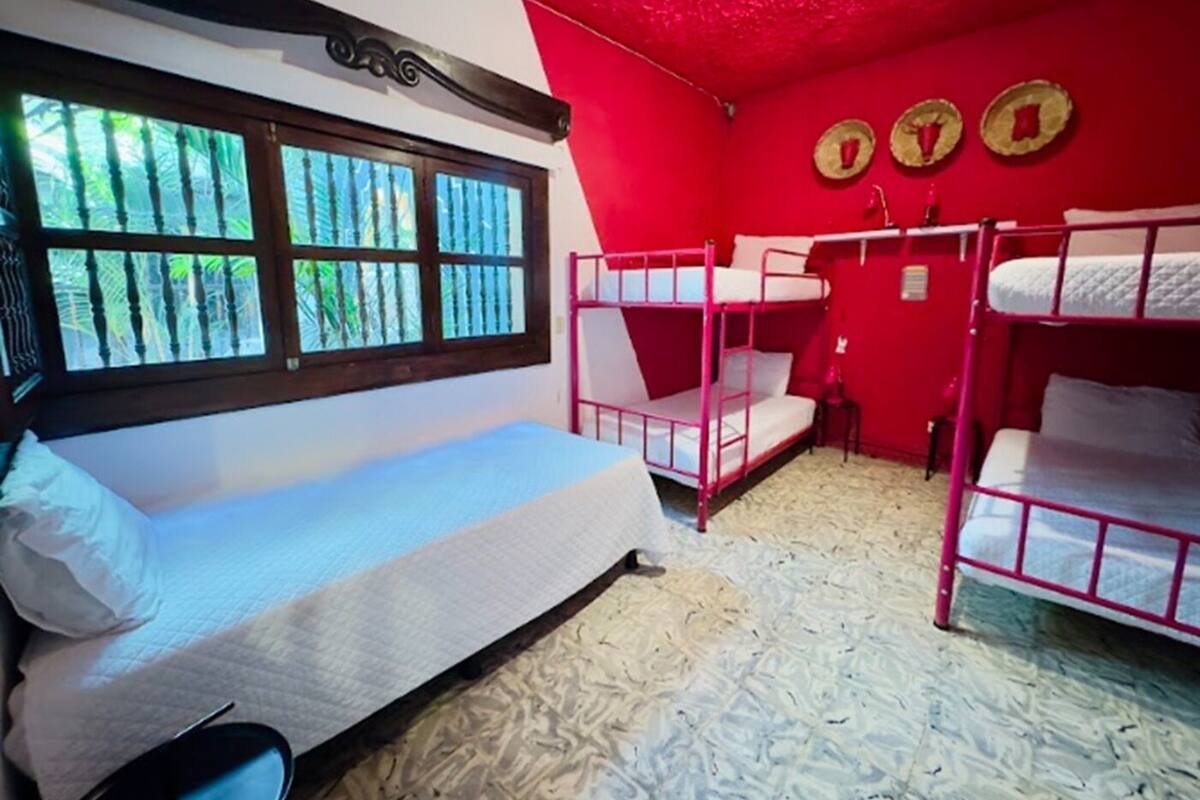 A room with bunk beds, a window with bars, and a red wall with three circular decorations.