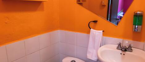 A bathroom with a white toilet, a sink, and a mirror. There are framed pictures on the wall and a towel hanging on the wall.