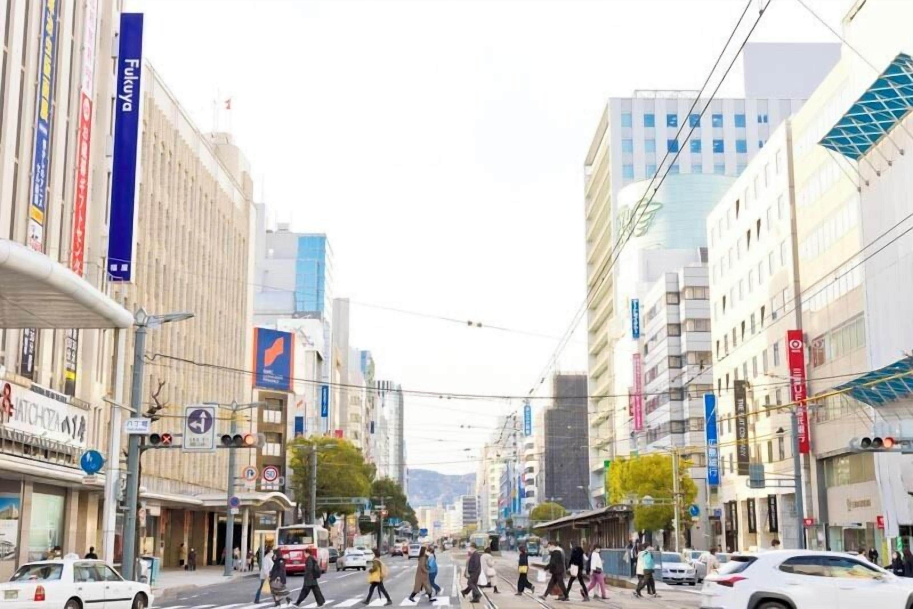 Una calle urbana concurrida con peatones, automóviles y edificios comerciales.