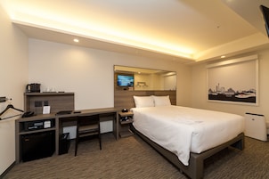 Una habitación de hotel con cama, escritorio y televisor.