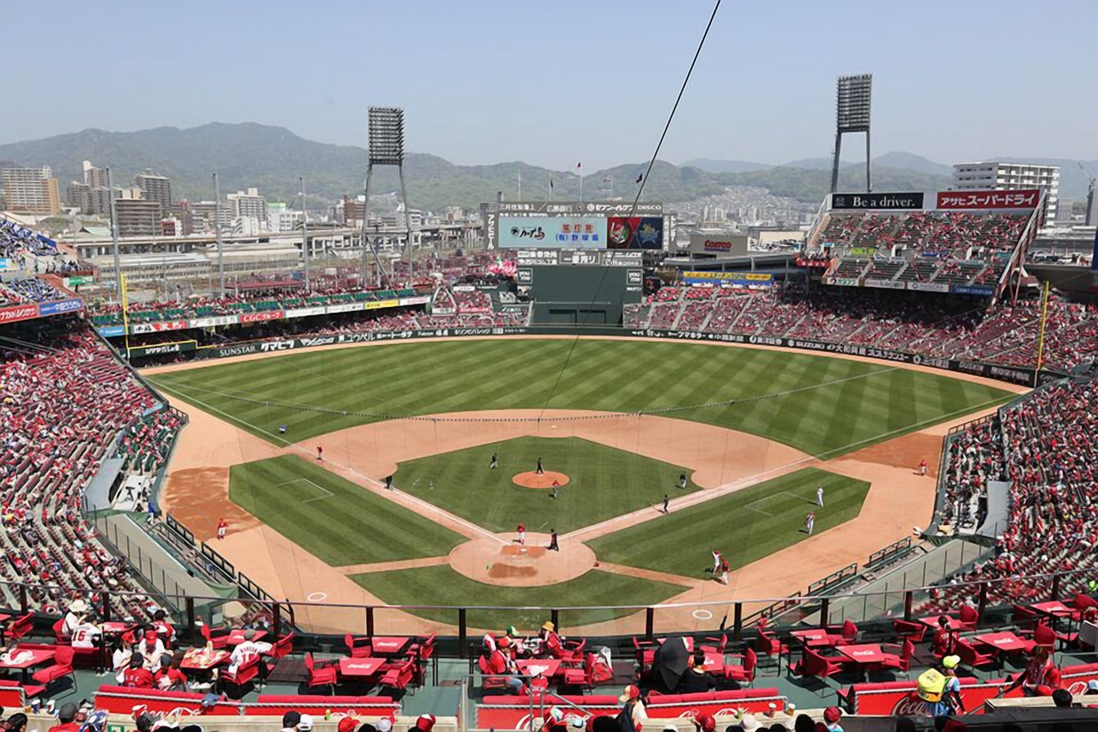 Un estadio de béisbol con una amplia zona de asientos, un campo central y un marcador.