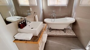 A modern bathroom with a freestanding bathtub, a vanity with a mirror, and a sink. - Lea Spa Hotel (Maafushi)