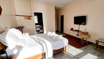 Una habitación de hotel moderna con una cama grande, un escritorio, un televisor y un equipo de aire acondicionado.