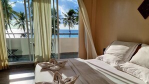 A hotel room with a bed, a view of the beach, and a table with towels. - Lea Spa Hotel (Maafushi)