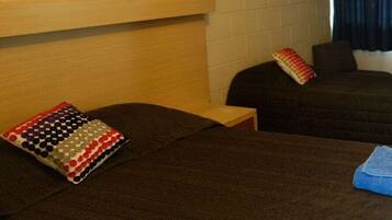 A hotel room with two beds, a wooden headboard, a small table, and a window with curtains.