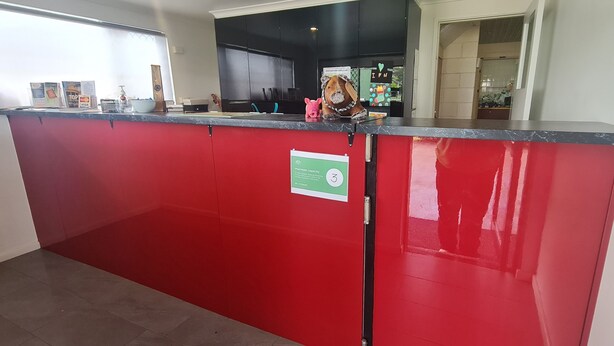 Balcão de recepção vermelho com placa verde indicando capacidade máxima.