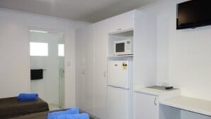 Quarto pequeno e compacto com uma cama, uma escrivaninha e um micro-ondas.