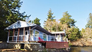 A cabin with a stone foundation, a covered deck, and a dock extending into a body of water. - New Listing! Adorable lakefront cabin, private dock, hot tub, gas grill, amazing views (Florence)