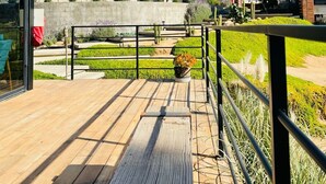 A modern building with a wooden deck, a concrete wall, and a metal railing.