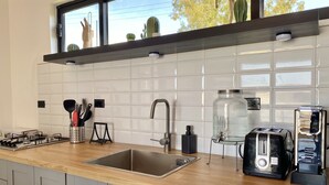 A modern kitchen with a wooden countertop, stainless steel sink, and a window above the sink.