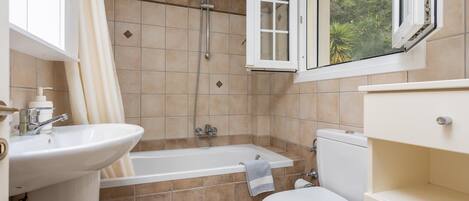 A bathroom with a bathtub, toilet, and sink.